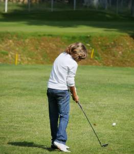 Young golfer performs a golf shot from the fairway.