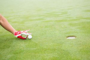 Golfer trying to flick ball into hole at the golf course