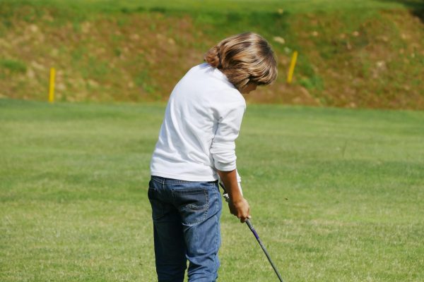 Young golfer performs a golf shot from the fairway.